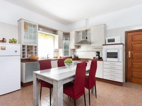 a white kitchen with a table and red chairs at Holiday Home Barreto by Interhome in Puerto de la Cruz