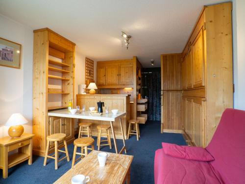 eine Küche mit Holzschränken sowie einem Tisch und Stühlen in der Unterkunft Apartment Belleville Caron-8 by Interhome in Les Menuires