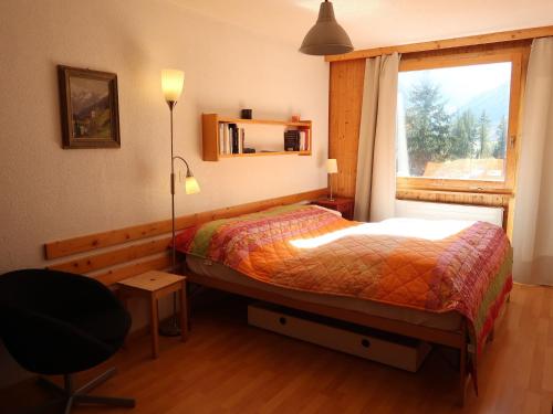 1 dormitorio con cama, ventana y silla en Studio Les Erables Apt 361 by Interhome, en Zinal