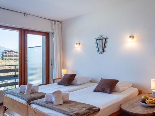two beds in a room with a window at Apartment Christiania 2 L1 by Interhome in Nendaz