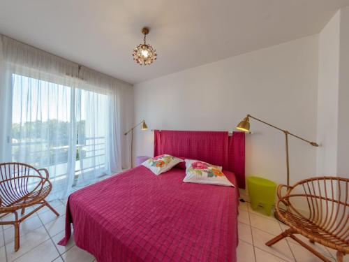 - une chambre avec un lit rose et deux chaises dans l'établissement Apartment Le Domino by Interhome, à Pontaillac