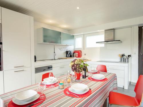 une cuisine blanche avec une table et des chaises rouges dans l'établissement Holiday Home Le Voilier by Interhome, à Kerlouan