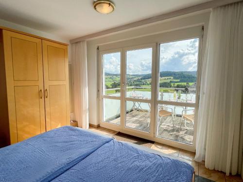 a bedroom with a blue bed and a large window at Apartment Schwarzwaldblick I by Interhome in Bernau im Schwarzwald