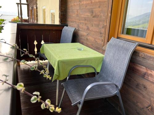 ピーゼンドルフにあるApartment Bauernhof Gasteg - PID230 by Interhomeの緑のテーブル付きのポーチにテーブルと椅子2脚