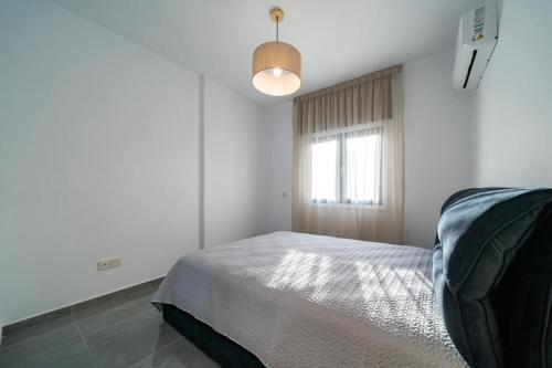 a white bedroom with a bed and a window at Stavri De'Lux Apartment in Larnaka