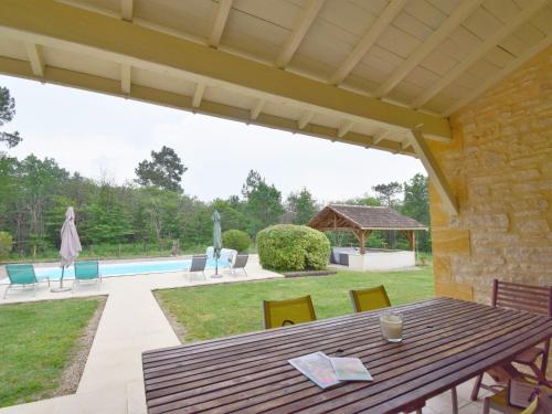 a patio with a wooden table and chairs and a pool at Holiday Home Au Cayroux - BSB302 by Interhome in Blanquefort-sur-Briolance