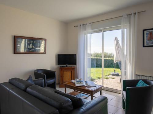 ル・コンケにあるHoliday Home Mer des Bosmen 2 - LCQ107 by Interhomeのリビングルーム(ソファ、椅子付)、ガラスのスライドドアが備わります。