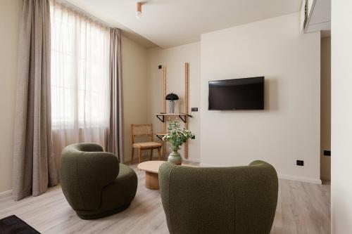 a living room with two chairs and a flat screen tv at Hôtel Gambettes - Entrée autonome, réception en ligne - Encore Mieux in Limoges