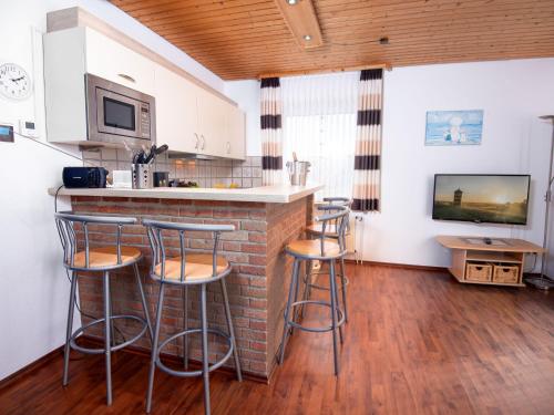 a kitchen with a bar with stools and a tv at Apartment Am Koper Sand-1 by Interhome in Norddeich