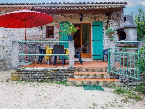 ein Haus mit einem Tisch und einem roten Regenschirm in der Unterkunft Holiday Home Lozard by Interhome in Barjac