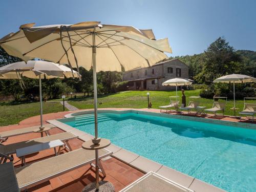 een zwembad met parasols en stoelen naast een huis bij Holiday Home Alighiero II by Interhome in Gabellino