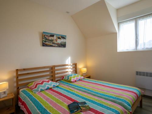 ein Schlafzimmer mit einem Bett mit einer bunten gestreiften Decke in der Unterkunft Holiday Home Mer d'Iroise 1 - LCQ104 by Interhome in Le Conquet