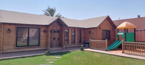 a wooden house with a playground in the yard at Antola Resort Al Rimal in Riyadh