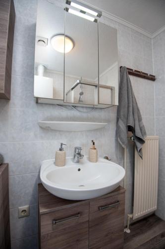 a bathroom with a white sink and a mirror at Holiday Home Storchennest by Interhome in Norddeich