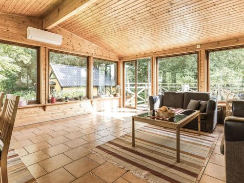 a living room with a table and chairs and windows at Holiday Home Kjuge Gula Huset by Interhome in Fjälkinge