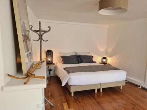 a white bedroom with a bed and two lamps at Le Relais de l'endormie in Nogent-sur-Seine