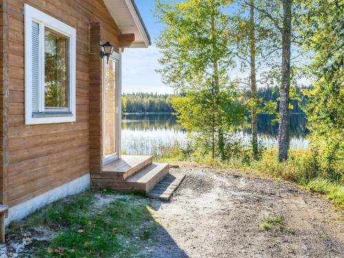 a house with a window and stairs next to a lake at Holiday Home Jussinlahti by Interhome in Kortteinen
