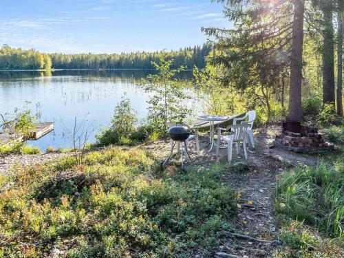 a picnic table and grill next to a lake at Holiday Home Lahdenpohja by Interhome in Kortteinen