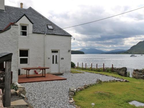 a house with a picnic table next to a body of water at Holiday Home Dunan by Interhome in Dunan