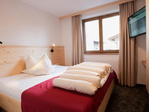 a bedroom with a bed with white sheets and a window at Apartment Falkner-13 by Interhome in Oberlängenfeld