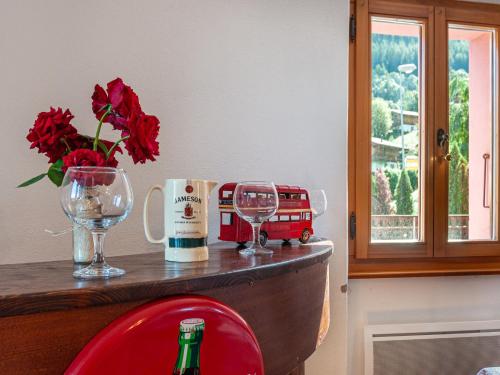 a bar with a bottle of wine and a vase of red flowers at Holiday Home Le Dahu by Interhome in Nendaz
