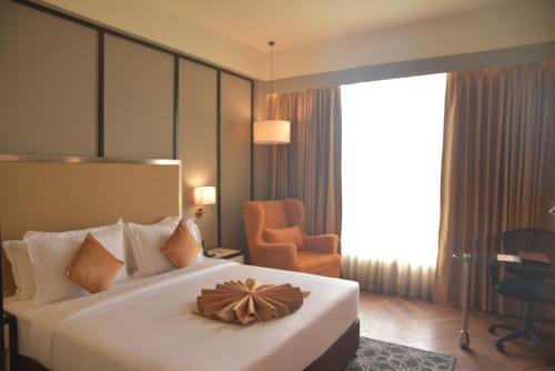 a hotel room with a large bed and a chair at Hotel Polo Towers Agartala in Agartala