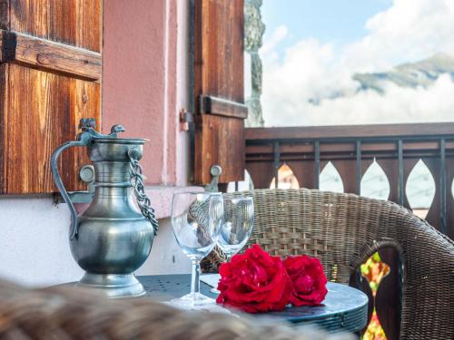 a table with a vase and two glasses and roses at Holiday Home Le Dahu by Interhome in Nendaz