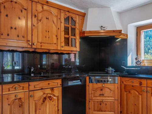 a kitchen with wooden cabinets and a black dishwasher at Holiday Home Le Dahu by Interhome in Nendaz