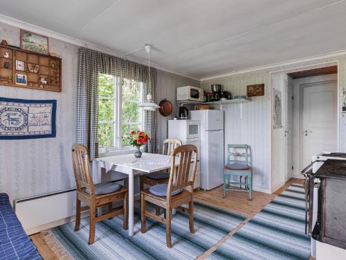 eine Küche mit einem Tisch und Stühlen sowie einem Kühlschrank in der Unterkunft Chalet Kasen Lillstugan by Interhome in Färgelanda