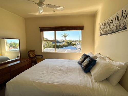 a bedroom with a large white bed with a window at Princes Retreat in Ngunguru