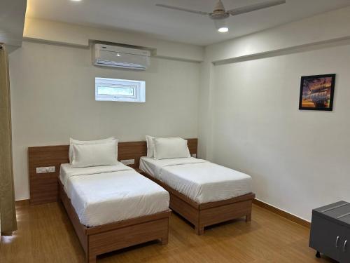 two beds in a room with white walls at Palladium Luxury Suites Financial District Unit II in Hyderabad