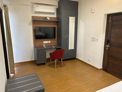 a room with a desk with a television and a red chair at Palladium Luxury Suites Financial District Unit II in Hyderabad