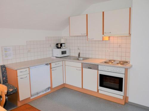 una pequeña cocina con armarios blancos y microondas en Apartment Silvretta by Interhome, en Kappl