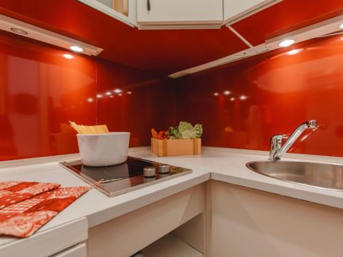 een keuken met rode muren en een wastafel bij Apartment Murmeltier by Interhome in Bad Gastein