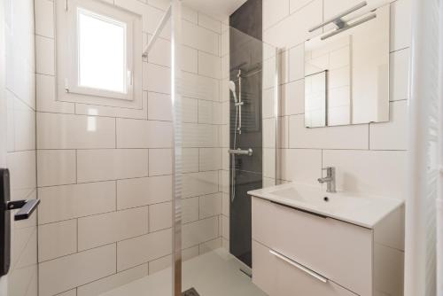 uma casa de banho branca com um lavatório e um chuveiro em T3 rénové avec balcon et parking - Saint-brieuc em Saint-Brieuc