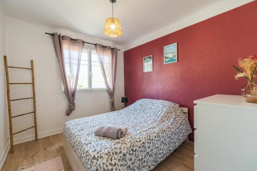 1 dormitorio con cama y pared roja en T3 rénové avec balcon et parking - Saint-brieuc en Saint-Brieuc