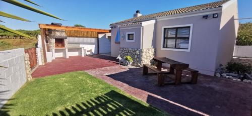 a small white house with a bench in the yard at Langebaan Escape Self Catering Accommodation in Langebaan