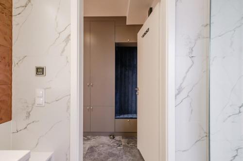 a bathroom with white marble walls and a doorway at FLORENCJA - nowy apartament w centrum miasta z zadaszonym parkingiem w cenie in Nowy Targ