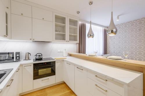 a white kitchen with white cabinets and appliances at FLORENCJA - nowy apartament w centrum miasta z zadaszonym parkingiem w cenie in Nowy Targ