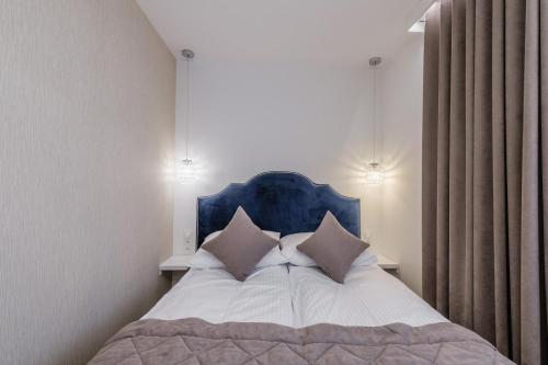 新塔爾格的住宿－FLORENCJA - nowy apartament w centrum miasta z zadaszonym parkingiem w cenie，一间卧室配有一张带蓝色床头板和枕头的床。