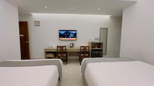 two beds in a room with a table and chairs at Priyo Nibash Stylish Residential Hotel in Dhaka