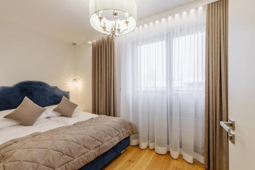 a bedroom with a bed and a large window at FLORENCJA - nowy apartament w centrum miasta z zadaszonym parkingiem w cenie in Nowy Targ