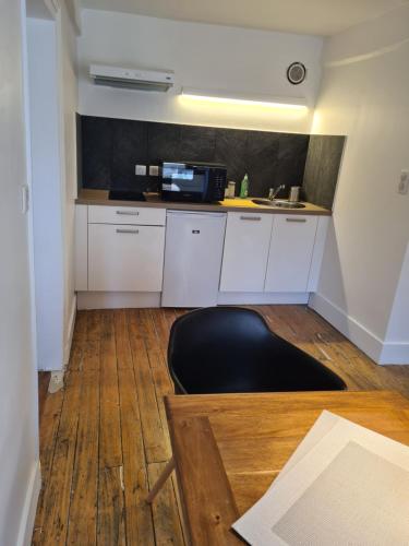 a kitchen with white cabinets and a black counter top at Le Relais de l'endormie in Nogent-sur-Seine