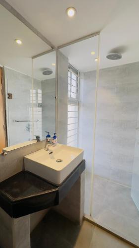 a white bathroom with a sink and a shower at Priyo Nibash Stylish Residential Hotel in Dhaka
