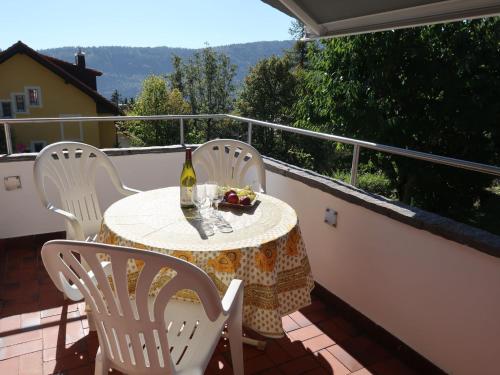 uma mesa com cadeiras e uma garrafa de vinho na varanda em Apartment Cochet 19 by Interhome em Sainte-Croix