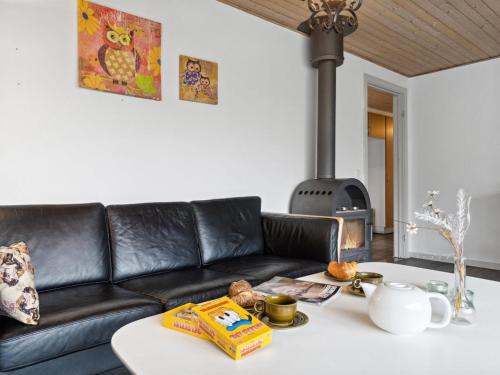 a living room with a black leather couch and a table at Holiday Home Kolle - 3-2km from the sea in Bornholm by Interhome in Vester Sømarken