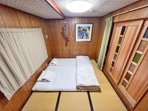 een kleine kamer met een bed aan de achterkant van een boot bij Bighem Maison in Izumi-Sano