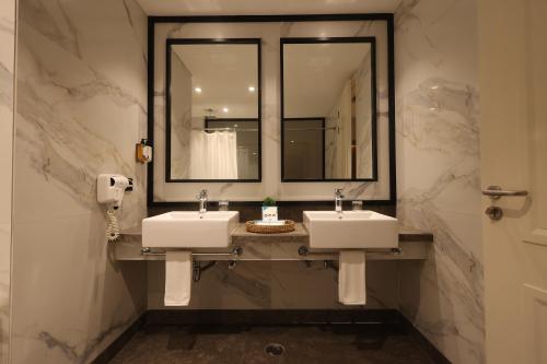 a bathroom with two sinks and a mirror at Hotel Polo Towers Agartala in Agartala