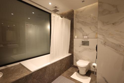 a bathroom with a tub and a toilet and a shower at Hotel Polo Towers Agartala in Agartala