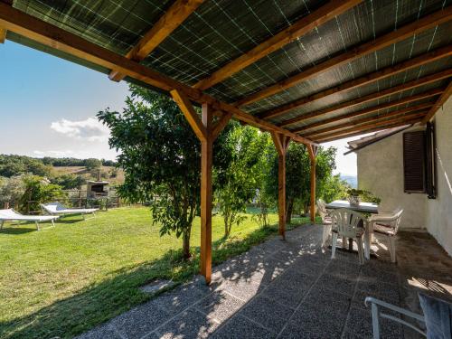 um pátio com uma mesa e cadeiras sob uma pérgula de madeira em Holiday Home Country House by Interhome em Montorgiali